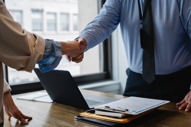 Two business professionals shaking hands to finalize a remote managed IT services partnership