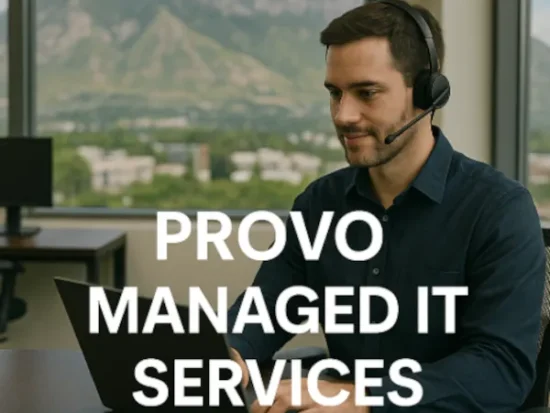 "IT professional wearing a headset working on a laptop in a modern Provo office with scenic mountain views in the background and the text 'Provo Managed IT Services' overlaid on the image."